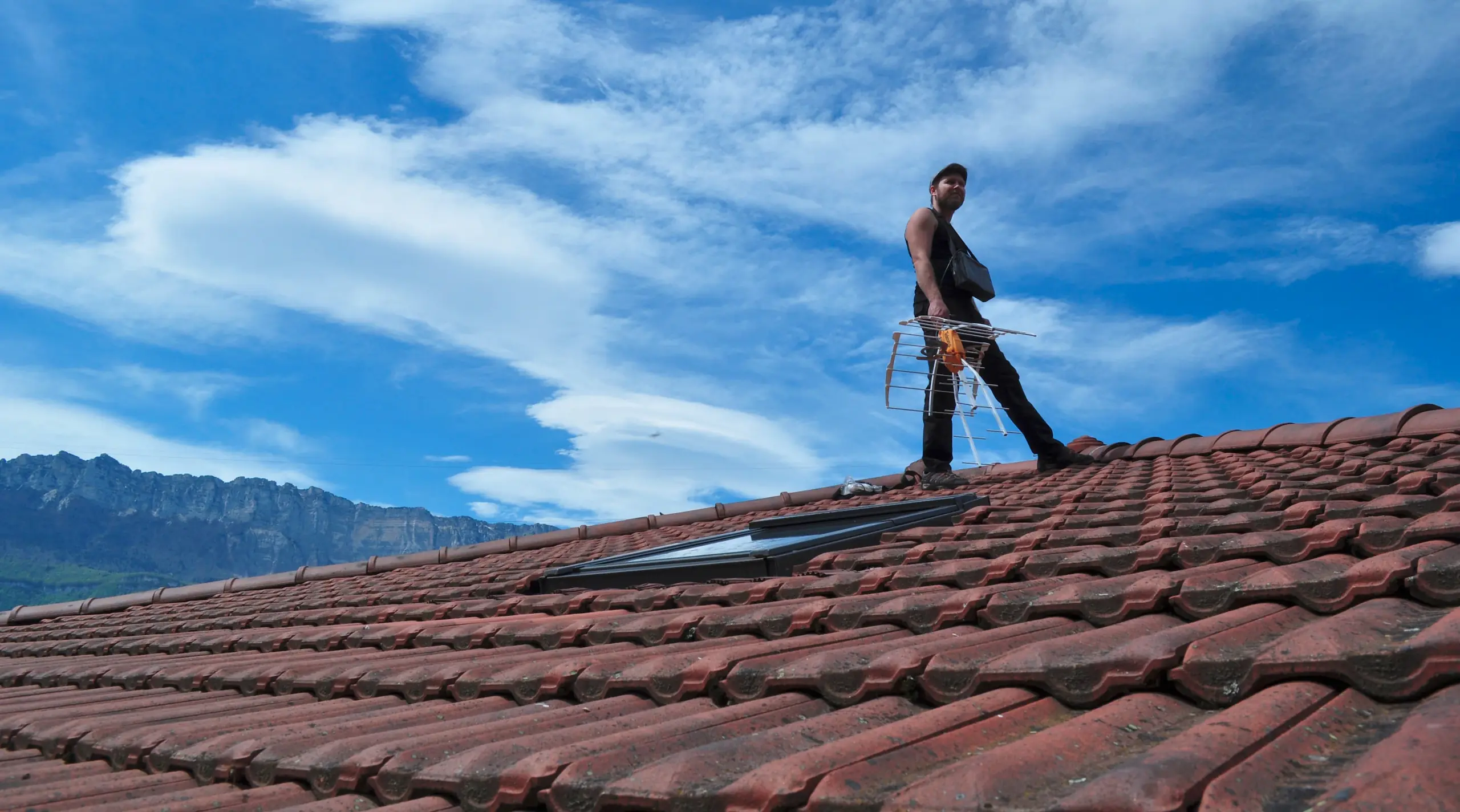 Antenniste qui installe une antenne râteau sur le toit d'une maison