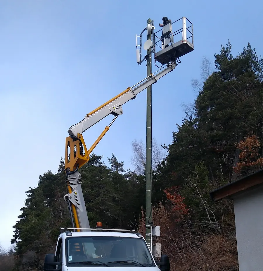 Artisan antenniste qui installe des antennes paraboliques en haut d'une nacelle déployée